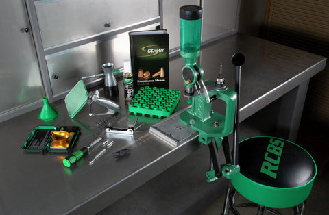 many green parts of a bullet reloading system on a stainless steel table